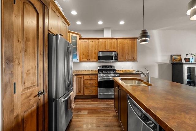 kitchen featuring recessed lighting, dark wood-type flooring, a sink, appliances with stainless steel finishes, and decorative light fixtures