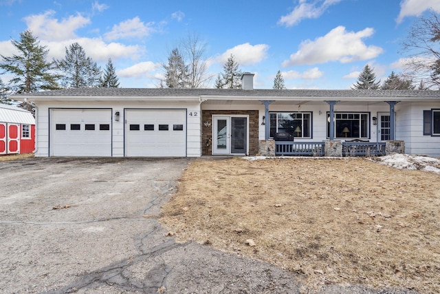 ranch-style home with driveway, an attached garage, a chimney, and a porch