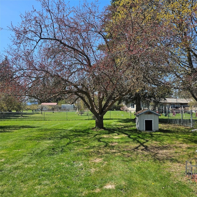 view of yard with an outdoor structure, fence, and a storage unit
