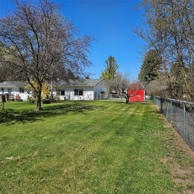 view of yard featuring an outbuilding, a fenced backyard, and a storage unit