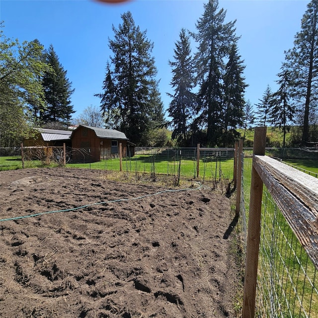 view of yard featuring an outbuilding, fence, and a barn