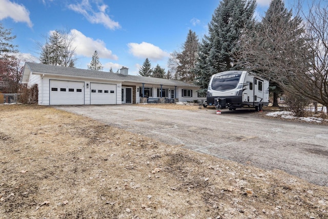 ranch-style house with aphalt driveway, a chimney, and a garage