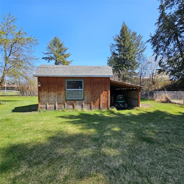 view of outdoor structure with fence, a carport, and an outdoor structure