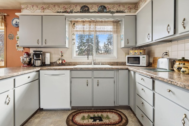 kitchen with a sink, white appliances, and decorative backsplash