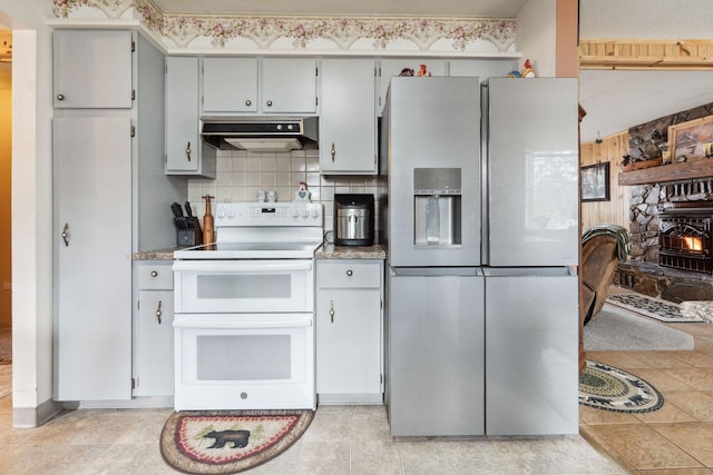 kitchen with stainless steel fridge, double oven range, under cabinet range hood, light countertops, and tasteful backsplash