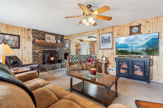 living area featuring ceiling fan, wooden walls, carpet, and visible vents