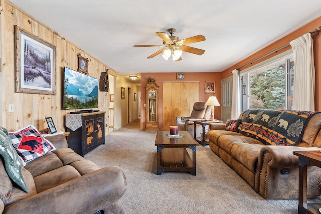 living room featuring light colored carpet, wooden walls, and ceiling fan