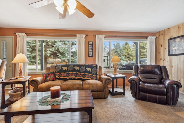 living room with light colored carpet, plenty of natural light, and wood walls