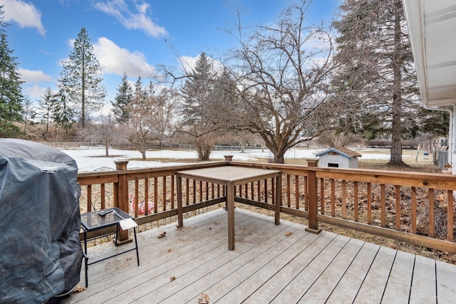 wooden deck with area for grilling, an outdoor structure, and a storage unit