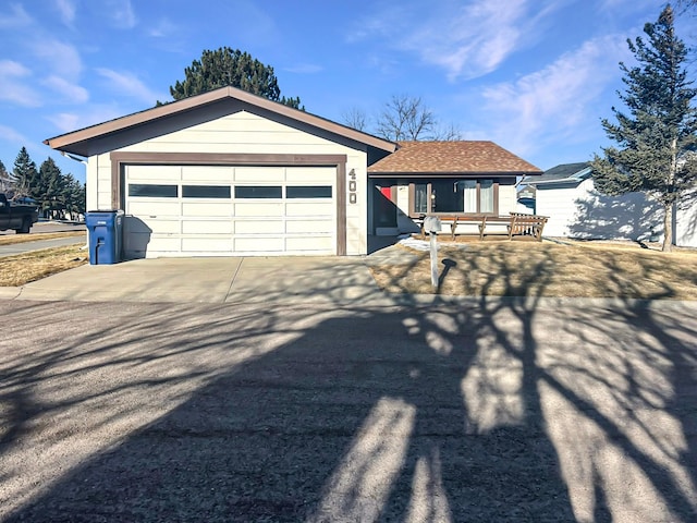 single story home with concrete driveway, roof with shingles, and an attached garage