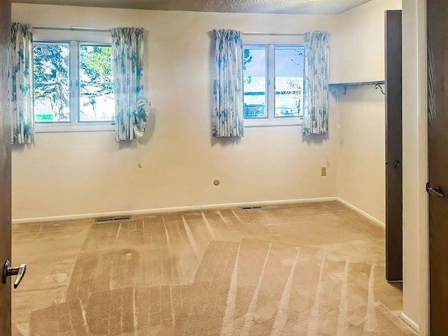 spare room featuring carpet floors, baseboards, and visible vents