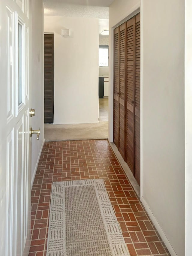 corridor with brick floor and baseboards