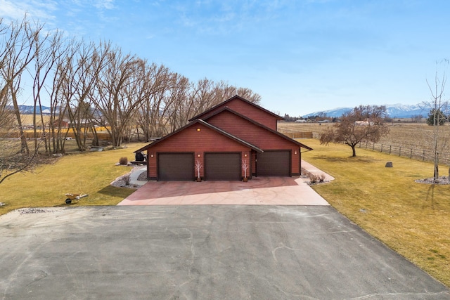 view of home's exterior with a lawn, driveway, fence, a mountain view, and a garage