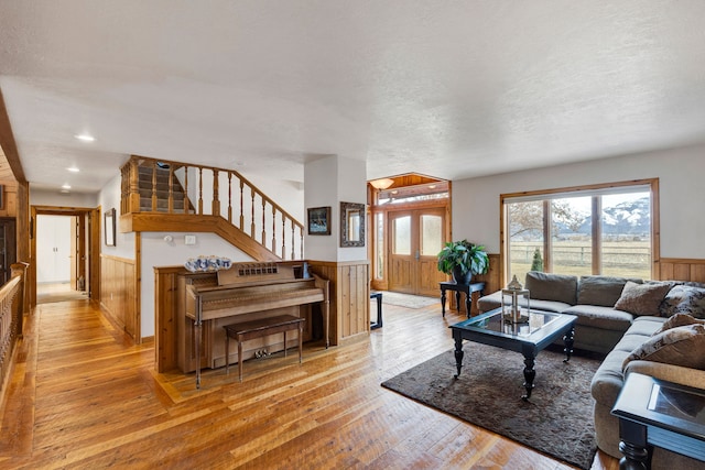 297 Christofferson Ln, Corvallis, MT 59828 - living room with wainscoting, stairs, light wood-style flooring, wooden walls, and a textured ceiling