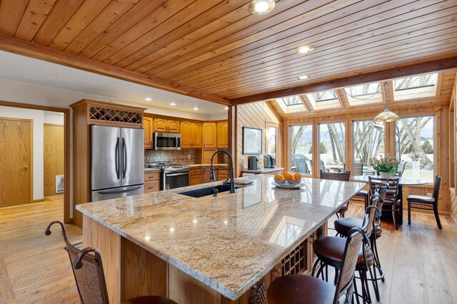 297 Christofferson Ln, Corvallis, MT 59828 - kitchen featuring appliances with stainless steel finishes, a sink, wood ceiling, brown cabinetry, and a kitchen bar