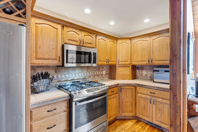 297 Christofferson Ln, Corvallis, MT 59828 - kitchen with stainless steel appliances, tile counters, light wood-type flooring, decorative backsplash, and recessed lighting