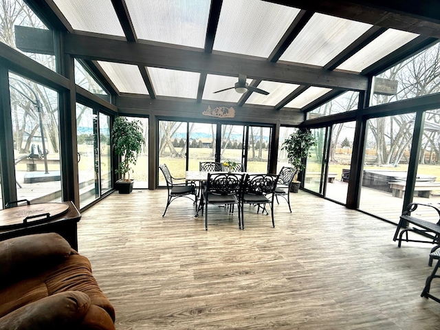 sunroom with lofted ceiling with beams, plenty of natural light, and ceiling fan