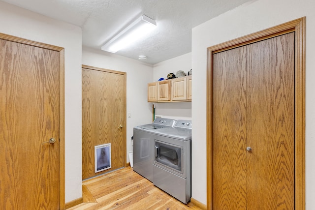 laundry room with light wood-style flooring, washer and dryer, and cabinet space
