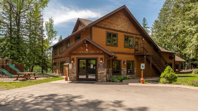 exterior space with stone siding, stairway, and a playground