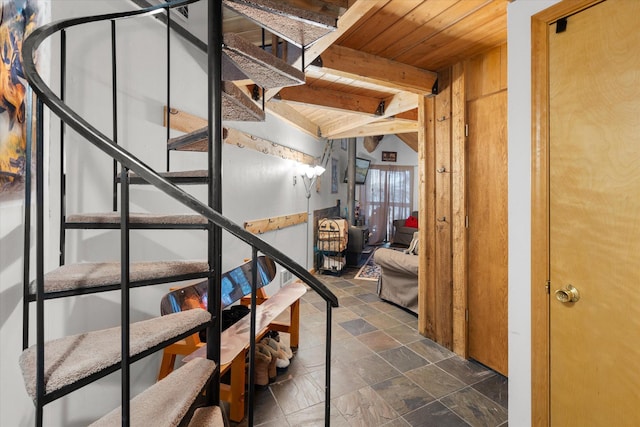 staircase with stone tile flooring, wooden ceiling, and beamed ceiling