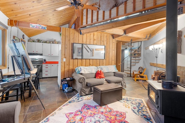 living area with stone tile floors, lofted ceiling, wooden ceiling, a wood stove, and stairs