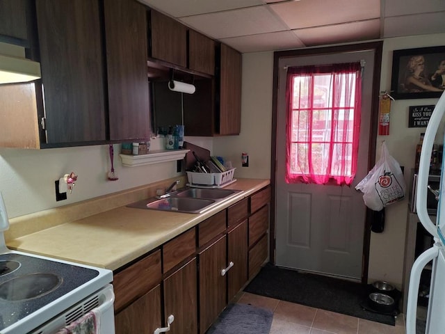 kitchen with light countertops, white electric range, a paneled ceiling, a sink, and light tile patterned flooring