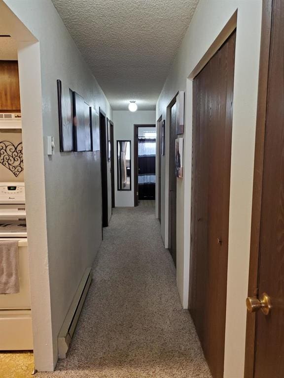 hall featuring light colored carpet, a textured ceiling, and baseboard heating