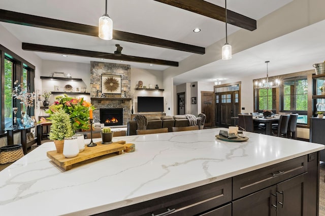 kitchen featuring hanging light fixtures, light stone countertops, a fireplace, and an inviting chandelier