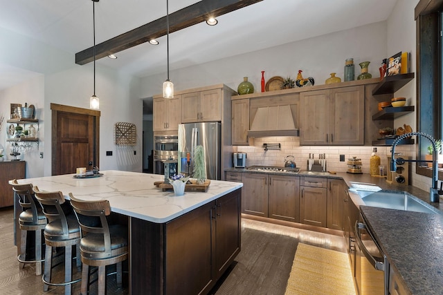 kitchen featuring open shelves, custom range hood, backsplash, appliances with stainless steel finishes, and a sink