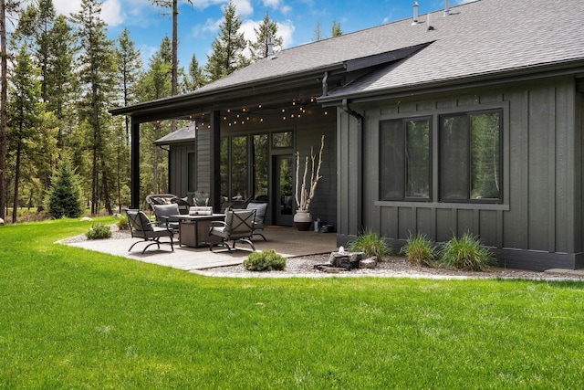 rear view of property featuring board and batten siding, a patio area, a lawn, and roof with shingles