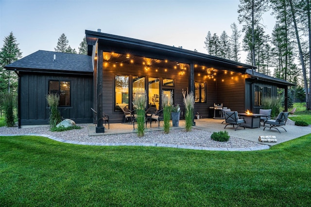 back of house featuring a yard, a patio, an outdoor fire pit, and board and batten siding