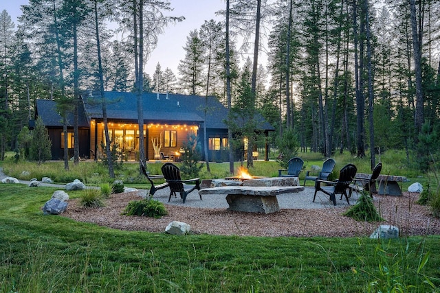 rear view of property with an outdoor fire pit, a lawn, and a patio area