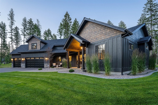 view of front of house with board and batten siding, a front yard, stone siding, and driveway