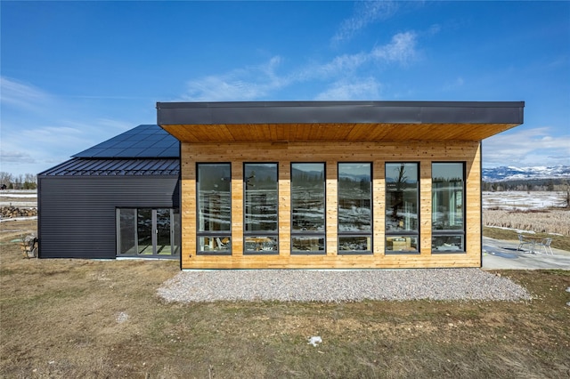 back of property with metal roof and roof mounted solar panels