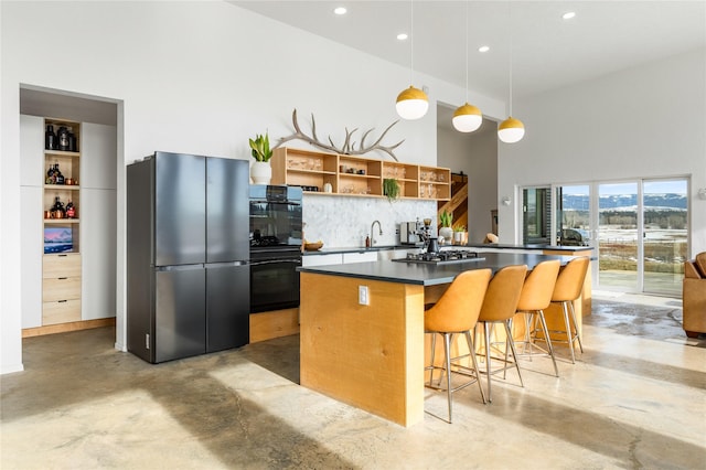 kitchen featuring dark countertops, a kitchen island, appliances with stainless steel finishes, concrete floors, and open shelves