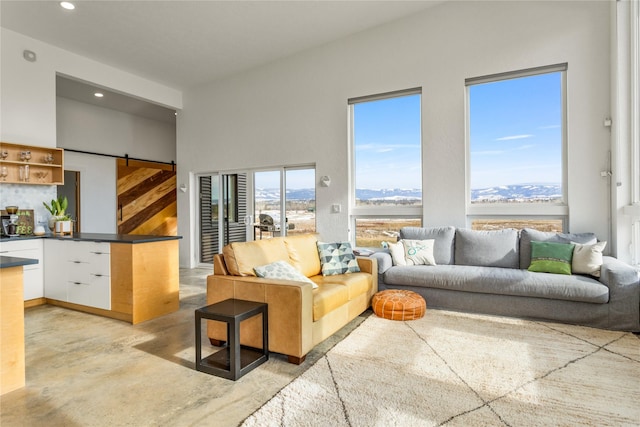 living area with a barn door, concrete floors, and recessed lighting