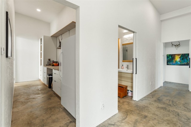 corridor featuring a sink and unfinished concrete floors