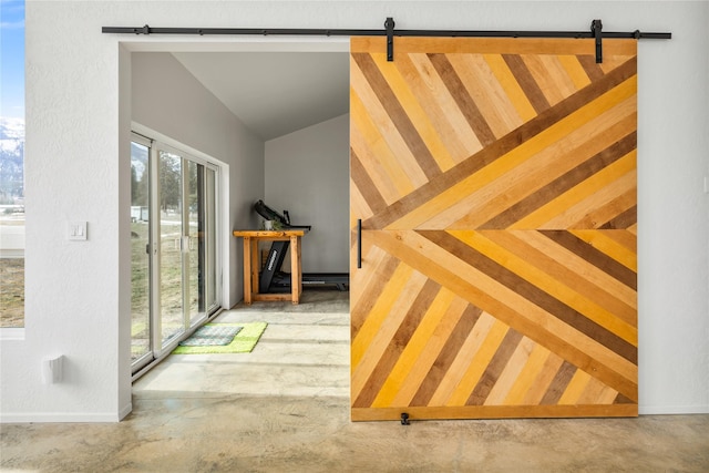 interior space featuring vaulted ceiling, concrete floors, baseboards, and a barn door