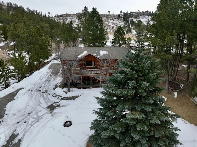 snow covered house featuring a chimney and a wooden deck