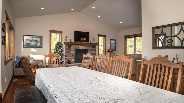 dining area with high vaulted ceiling, recessed lighting, dark wood finished floors, and a stone fireplace