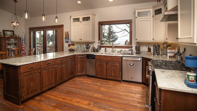 kitchen featuring appliances with stainless steel finishes, dark wood-style flooring, a peninsula, under cabinet range hood, and a sink