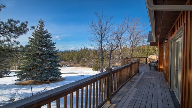 snow covered deck featuring a forest view