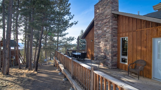 exterior space featuring board and batten siding, a chimney, and a deck