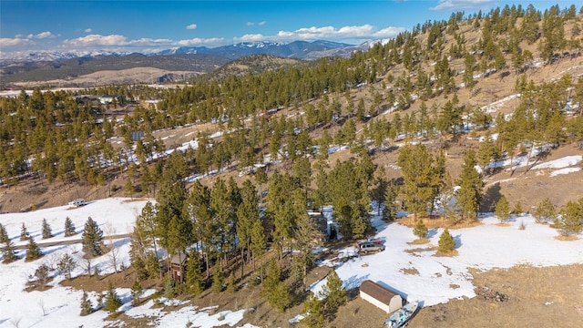 snowy aerial view with a mountain view and a wooded view