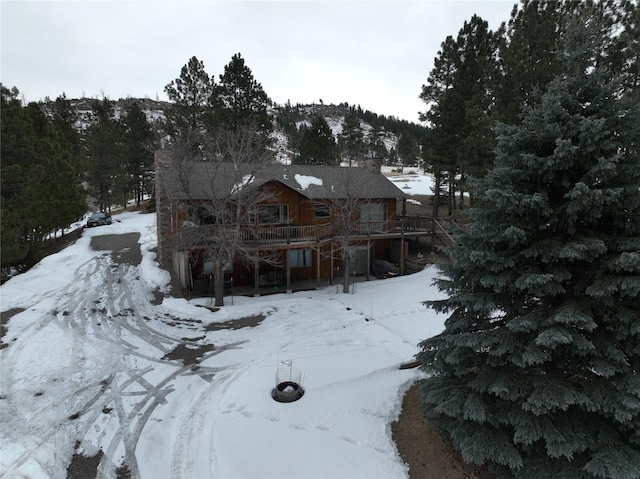 snow covered rear of property with a deck and stairway