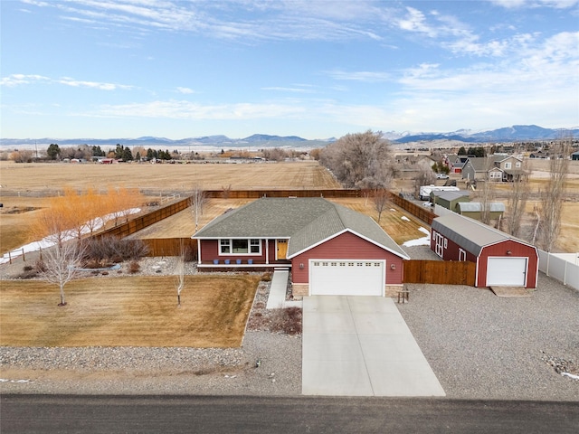 view of front of property with fence, driveway, a shingled roof, stone siding, and a mountain view