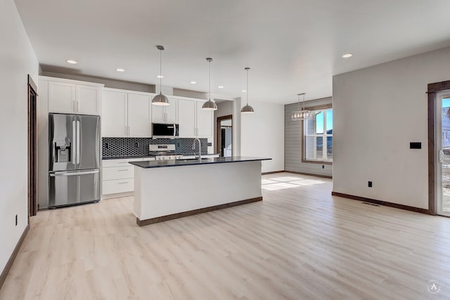 kitchen featuring decorative backsplash, dark countertops, appliances with stainless steel finishes, light wood-type flooring, and white cabinetry