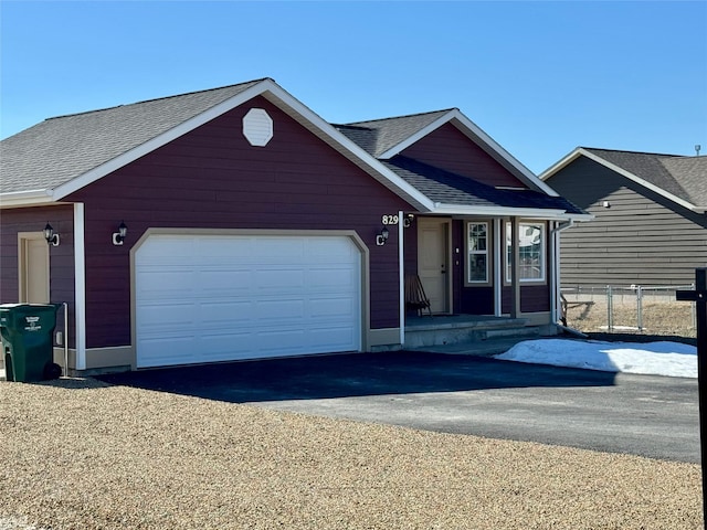 ranch-style home with a garage, a shingled roof, and aphalt driveway