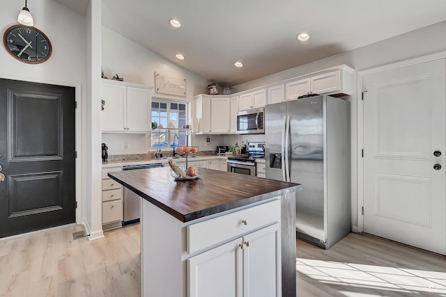 kitchen featuring a kitchen island, white cabinetry, stainless steel appliances, and wooden counters