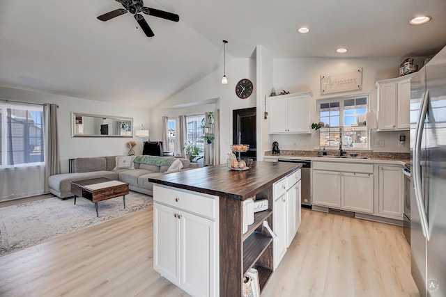 kitchen featuring light wood-style flooring, wood counters, white cabinetry, open floor plan, and appliances with stainless steel finishes